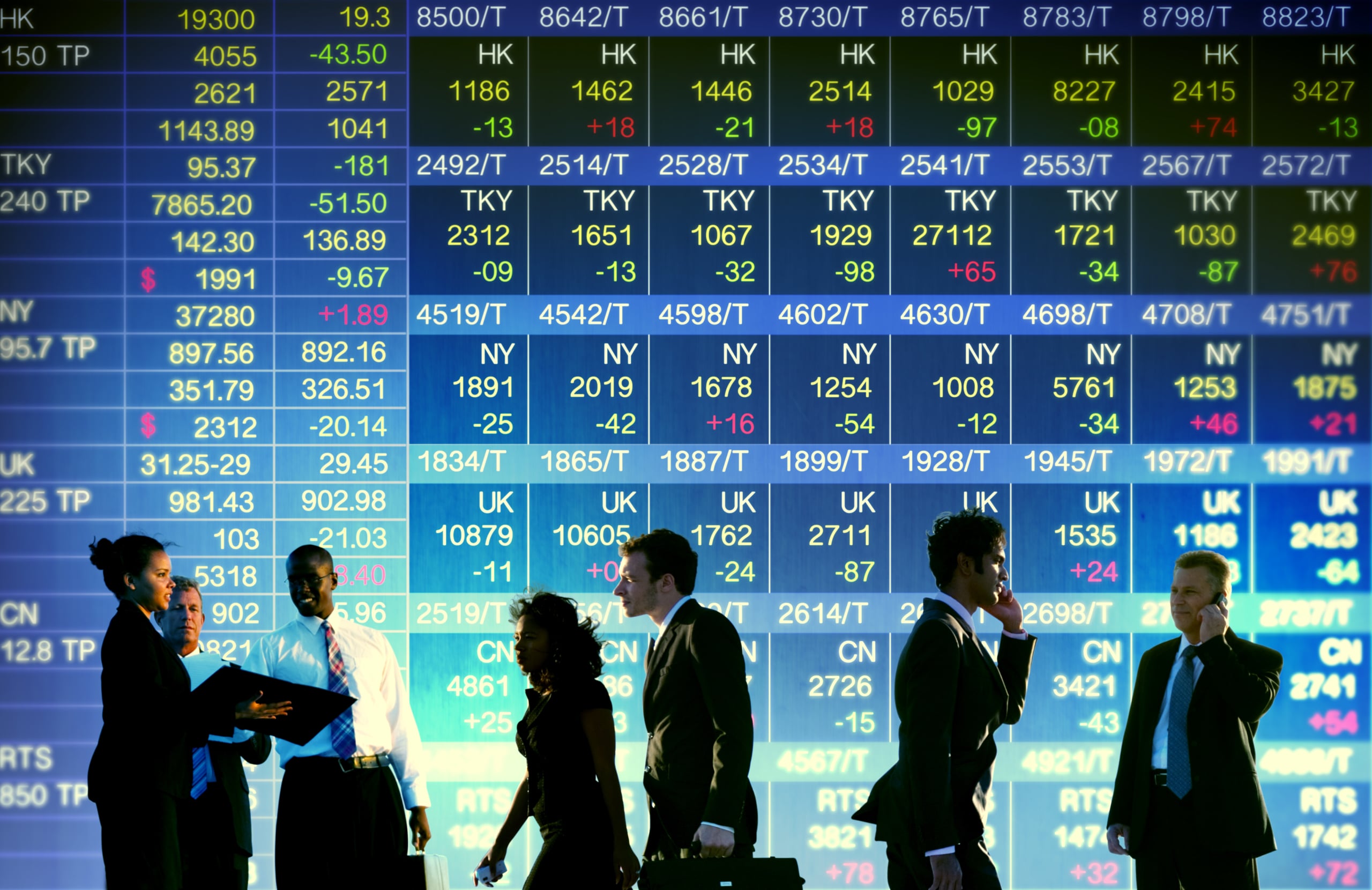 people standing in front of a stock board