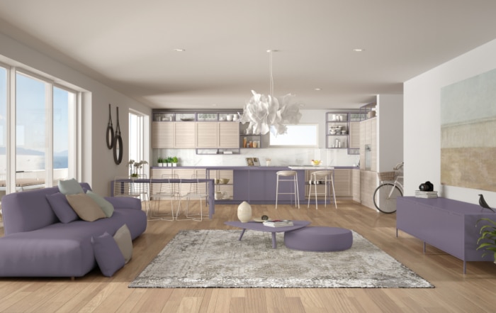 An open floor plan with purple furniture and white walls and a white ceiling. Natural wood floors.