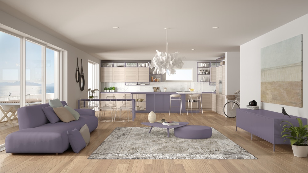 An open floor plan with purple furniture and white walls and a white ceiling. Natural wood floors.