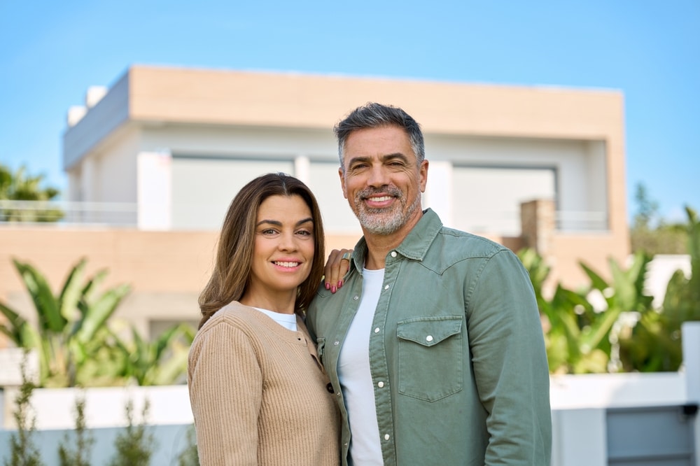 Happy couple in front of a house they just bought
