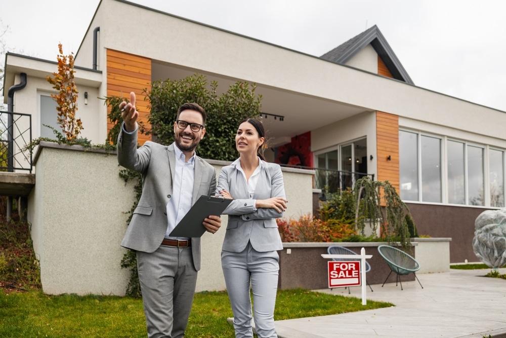 real estate agent and buyer standing in front of her new home