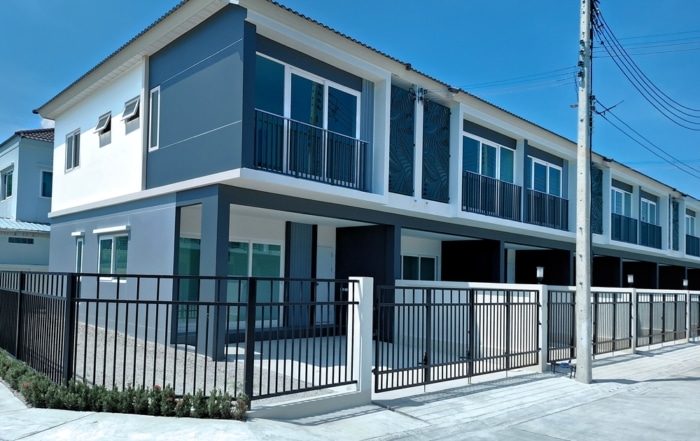 Row of blue and white townhouses with a black fence around them