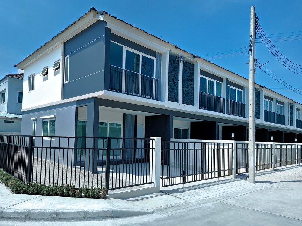 Row of blue and white townhouses with a black fence around them